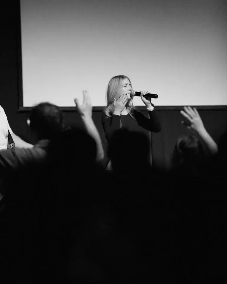 A woman singing during worship at Pillar Church